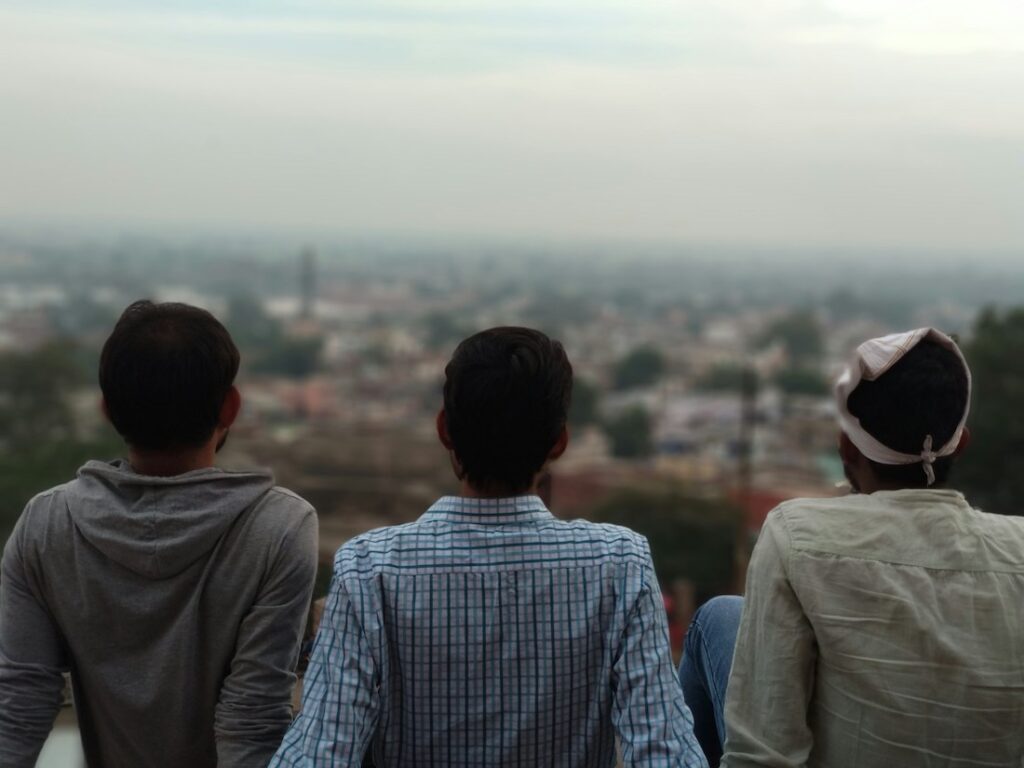 three men sitting together looking out over a city